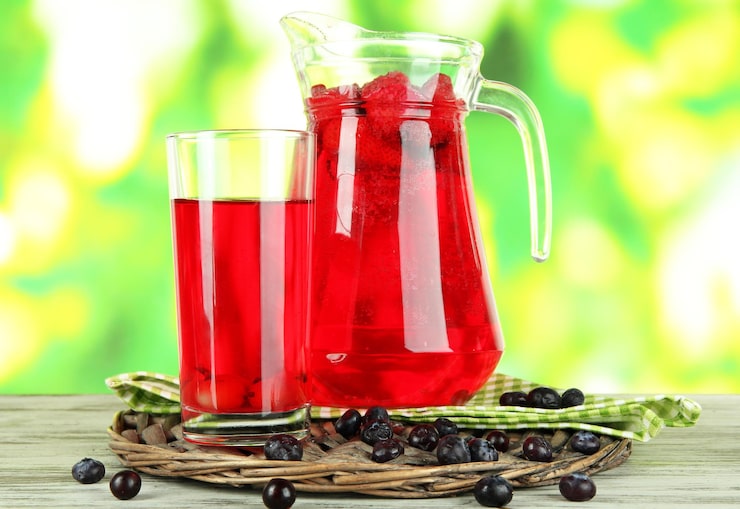 Photo bình và ly đựng nước trái cây trên khăn ăn trên bàn gỗ trên nền thiên nhiên