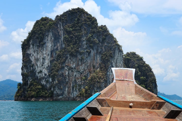 Miễn phí Photo thuyền gỗ trên biển được bao quanh bởi các thành tạo đá dưới bầu trời xanh nhiều mây