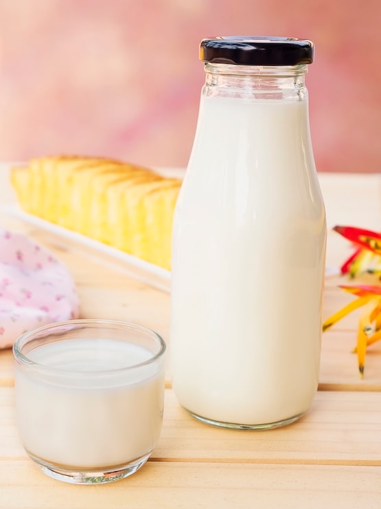 Photo gratuit bouteille avec verre de gâteau au lait et beurre sur une table en bois blanche.
