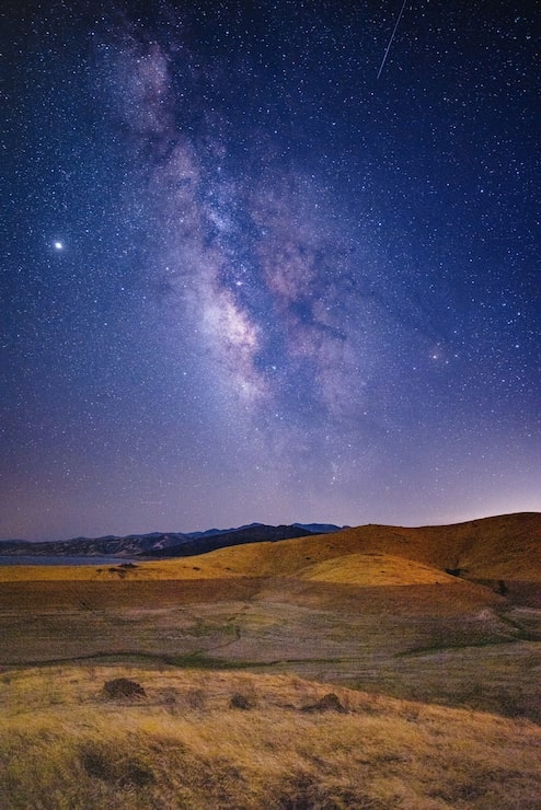 Photo gratuit champ d'herbe brune et verte sous un ciel bleu avec des étoiles pendant la nuit