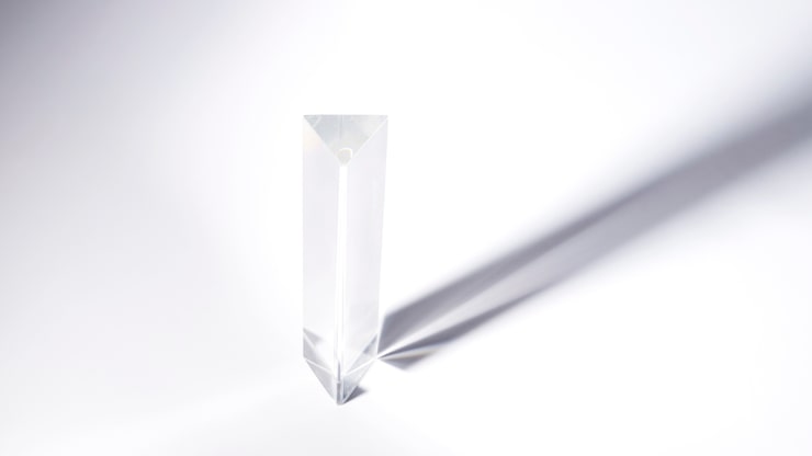 Photo gratuit cristal de prisme triangulaire avec une ombre sombre sur fond blanc