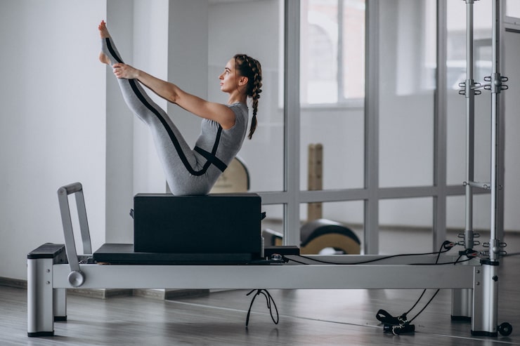 Photo gratuit une femme pratiquant le pilates dans un réformateur de pilates