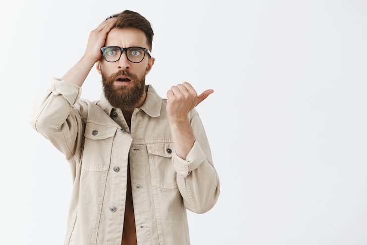 Photo gratuit homme barbu confus et inquiet dans des verres posant contre le mur blanc