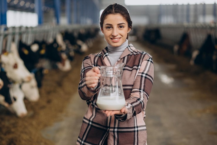 Photo gratuit jeune femme debout avec pot à lait à l'étable