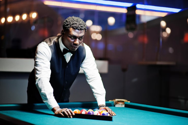 Photo gratuit un jeune homme africain beau portant une chemise blanche un gilet noir et un nœud papillon joue au billard