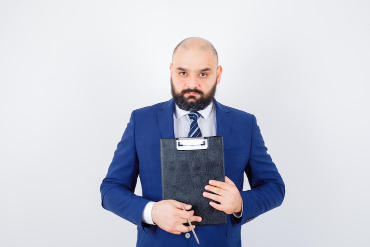 Photo gratuit jeune homme en chemise blanche, veste tenant le presse-papiers et regardant pensif, vue de face.