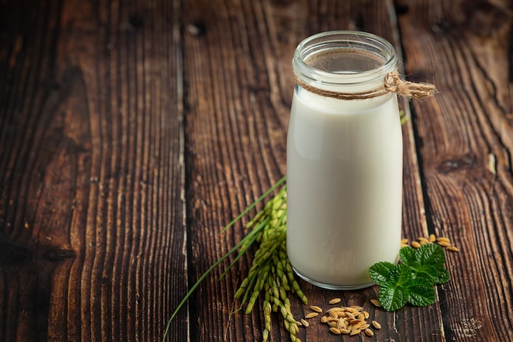 Photo gratuit jug de lait de riz avec plante de riz et graines de riz sur le sol en bois