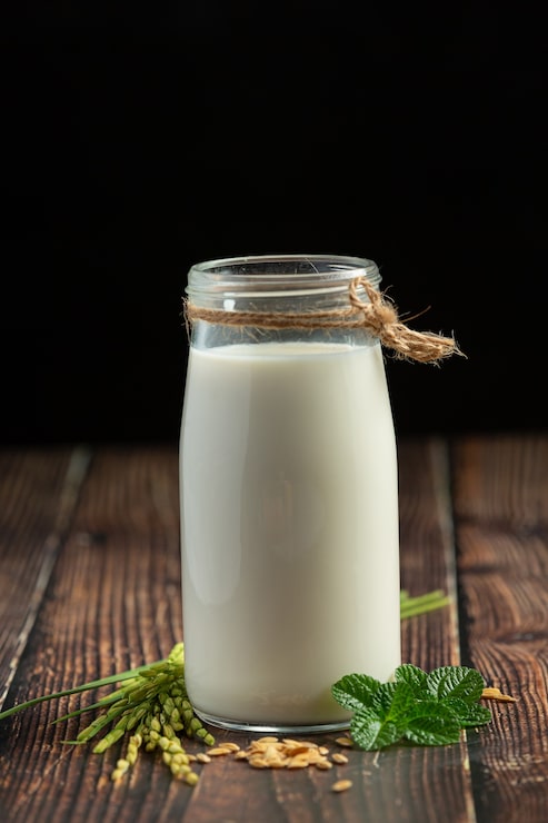 Photo gratuit jug de lait de riz avec plante de riz et graines de riz sur le sol en bois