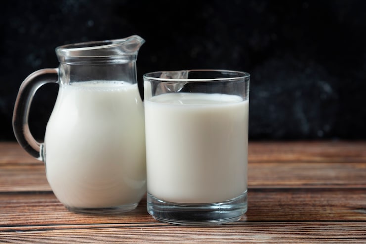 Photo gratuit lait frais dans une tasse et une cruche sur une table en bois.