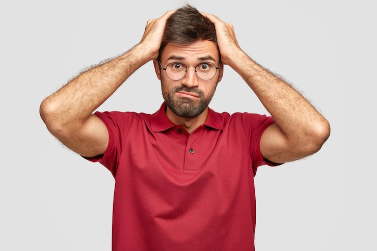 Photo gratuit un mec frustré et stressant garde les mains sur la tête, fronce les sourcils, panique