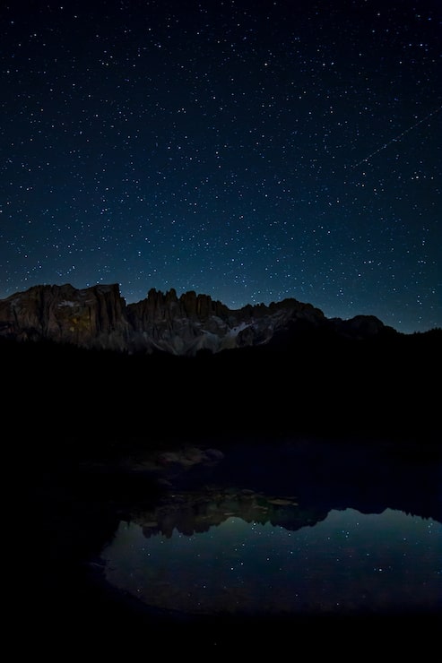 Photo gratuit paysage à couper le souffle du ciel étoilé et des falaises rocheuses se reflétant sur le lac pendant la nuit