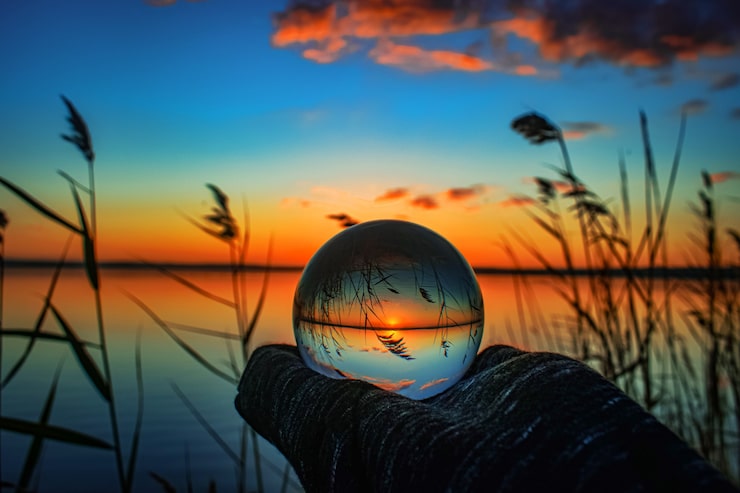 Photo gratuit photographie de boule de lentille de cristal créative d'un lac avec de la verdure autour à l'aube