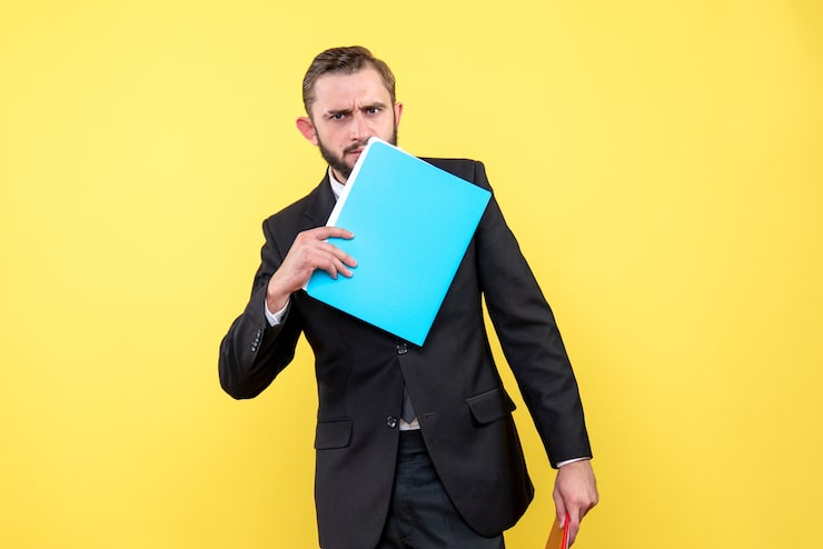Photo gratuit vue de face du jeune homme d'affaires réfléchi touche sa face inférieure avec dossier bleu sur jaune