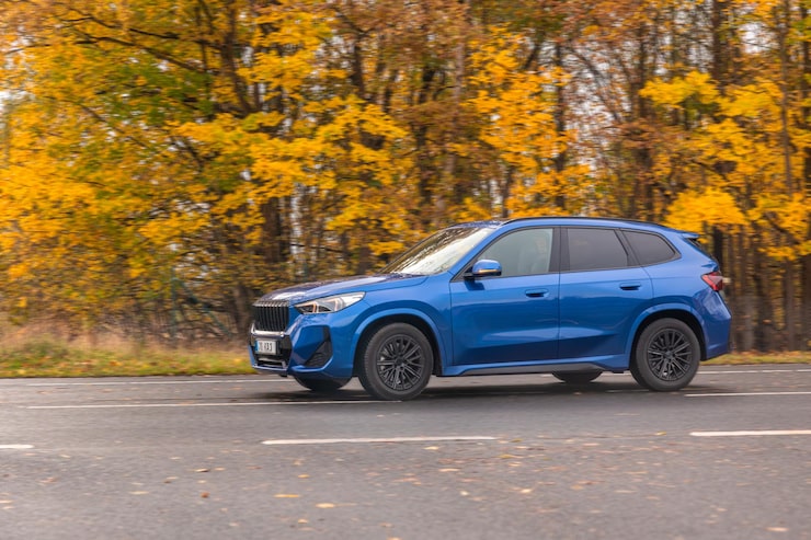 Photo gratuit vue latérale d'un crossover bleu roulant sur une route d'automne, voiture en mouvement