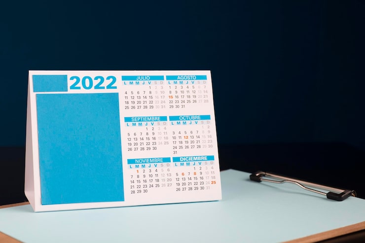 Photo 2022 mois calendaires en espagnol sur table de bureau en bois bloc-notes avec fond bleu