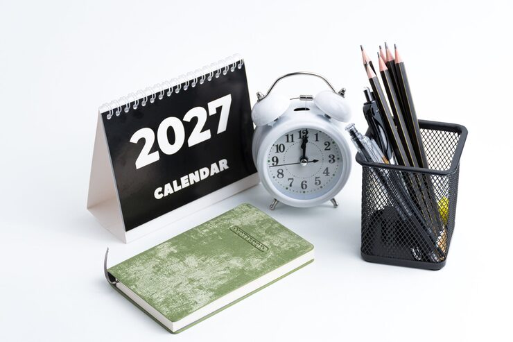 Photo aménagement de bureau avec calendrier 2027, horloge, crayons et billets de roupie