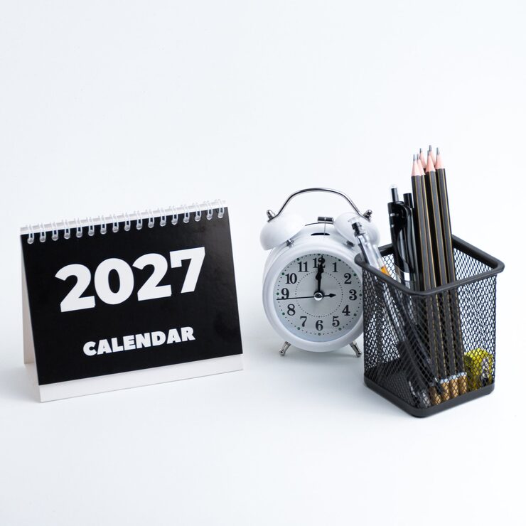 Photo aménagement de bureau avec calendrier-horloge 2027 et crayons, isolé sur blanc