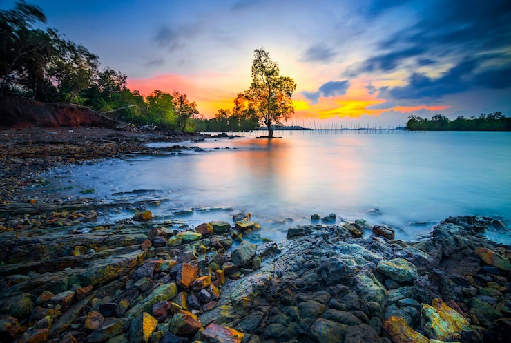 Photo beau coucher de soleil avec des rochers le long de la plage