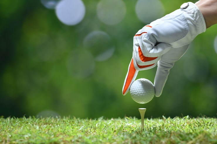 Photo main tenir la balle de golf avec tee sur terrain de golf