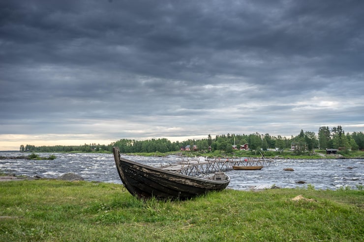 Foto forlatt båt på elvebredden mot skyet himmel