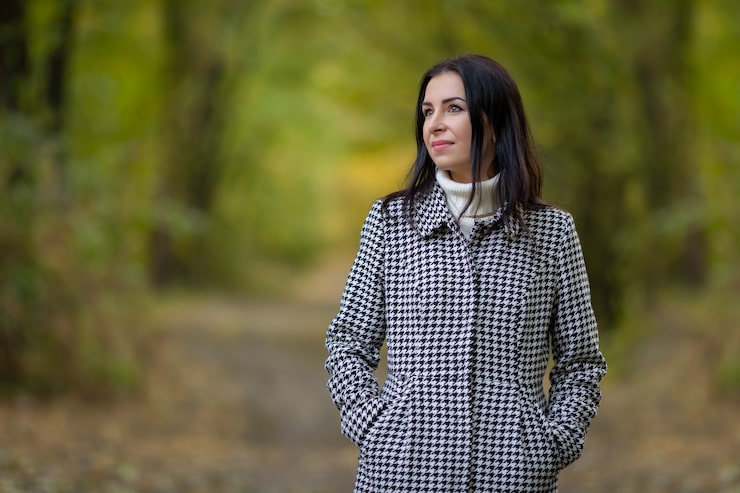 Foto en ung pige i en hvid sweater og ternet frakke i en efterårspark omgivet af løv. høj kvalitets foto