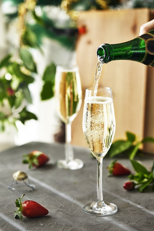 Bild glas med champagne och jordgubbar med gröna blad i bakgrunden