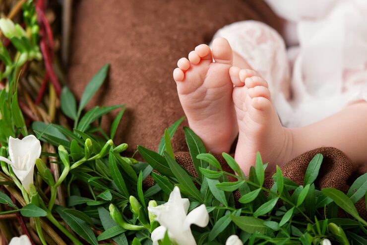 Foto nærbillede af nyfødte babyfødder på strikket plaid og blomster