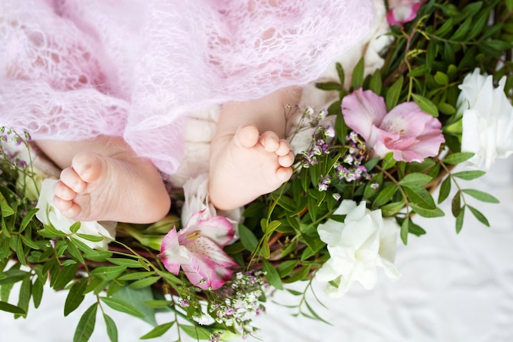 Foto nærbillede af nyfødte babyfødder på strikket plaid og blomster