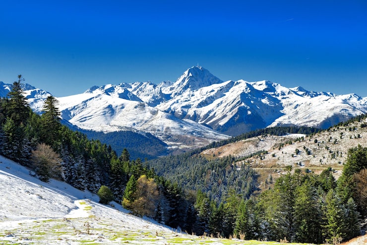 Bild naturskön vy över snötäckta berg mot klarblå himmel