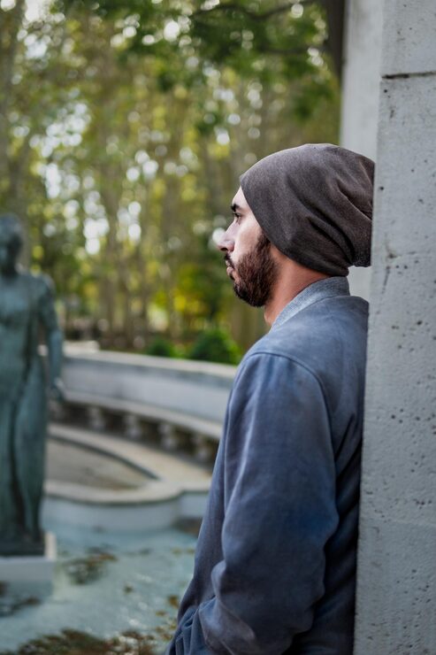 Foto park kontemplation profil af en mand, der læner sig op ad en mur med udsigt over en statue