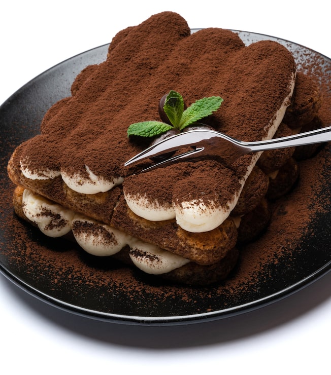 Bild portion av klassisk tiramisudessert på keramisk tallrik isolerad på vit bakgrund