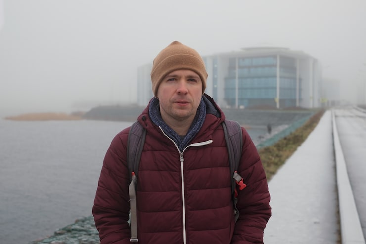 Foto ung trist kaukasisk mand i varm hat og frakke, der står alene