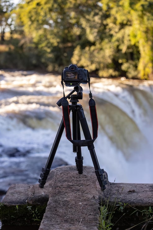 Fotoğraf bir şelalenin seçici odaklı fotoğrafını çekmek için tripod üzerindeki fotoğraf makinesinin yakın çekimi