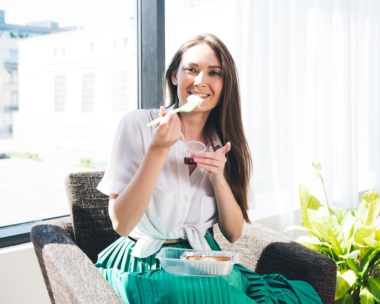 Foto een vrouw eet een plakje komkommer en draagt een groene rok.