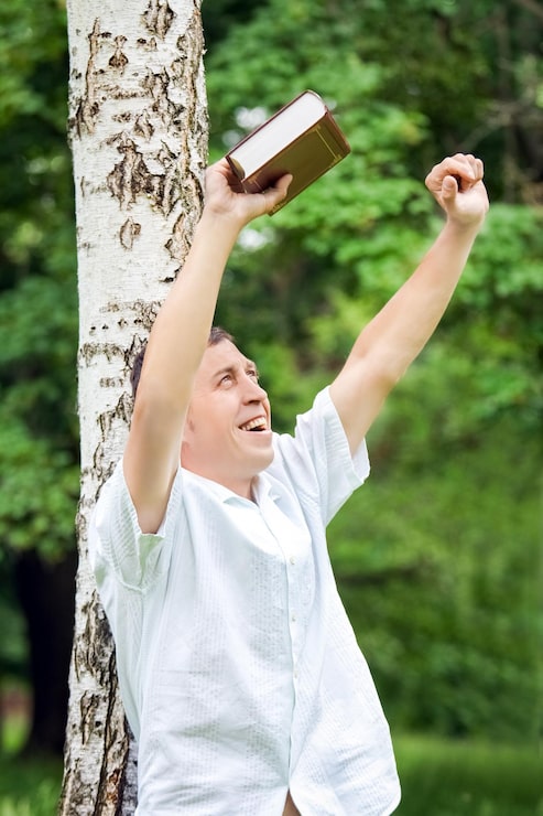 gelukkige man die een bijbel leest in een park op de natuur