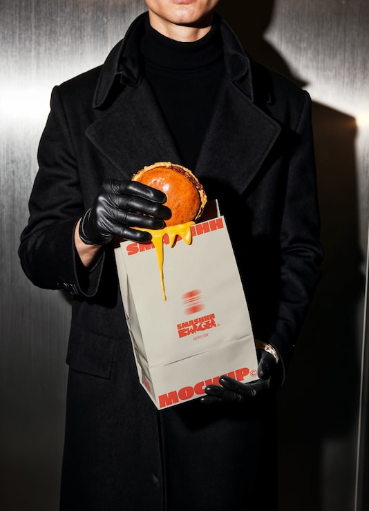 Stylish man holding a burger in a takeaway bag