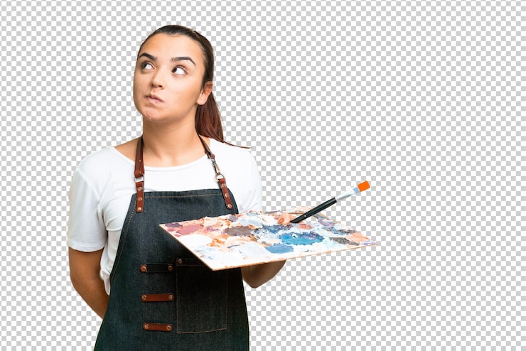 PSD mujer joven artista sosteniendo una paleta sobre un fondo clave de croma aislado y mirando hacia arriba