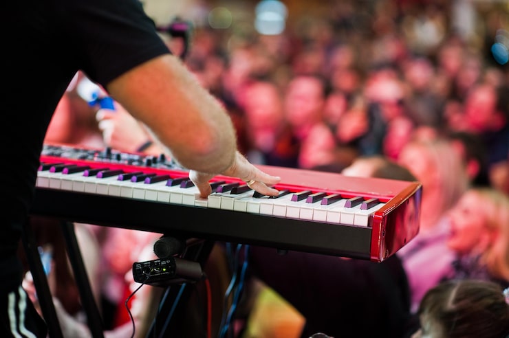 Ücretsiz Fotoğraf sanatçı, konser salonunda sahnedeki audio piyanosunda insanların arkasında çalıyor.