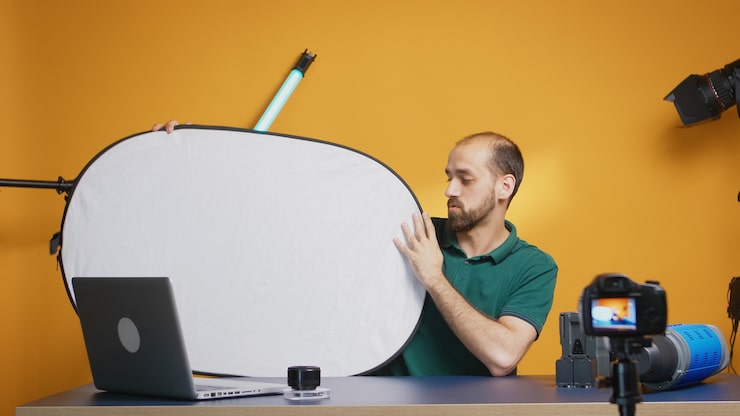 Ücretsiz Fotoğraf stüdyoda beyaz ışık reflektörü hakkında vlog kaydeden fotoğrafçı. i̇ş için profesyonel stüdyo video ve fotoğraf ekipmanı teknolojisi, fotoğraf stüdyosu sosyal medya yıldızı ve etkileyicisi