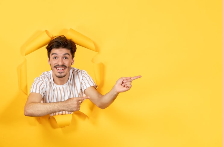 Ücretsiz Fotoğraf yırtık sarı kağıt yüzeyde duran genç adam