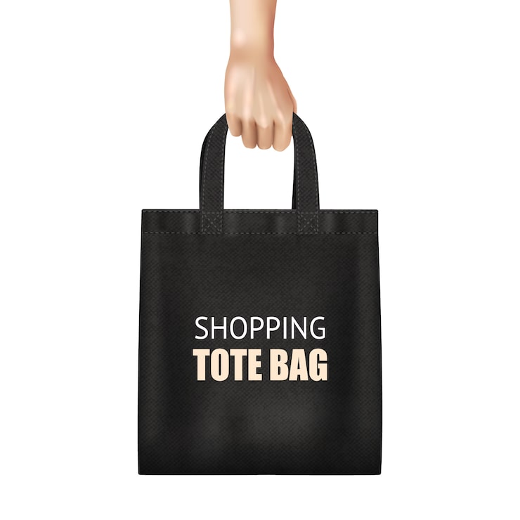 Vector gratuito mano que sostiene la bolsa de asas negra de moda de las compras