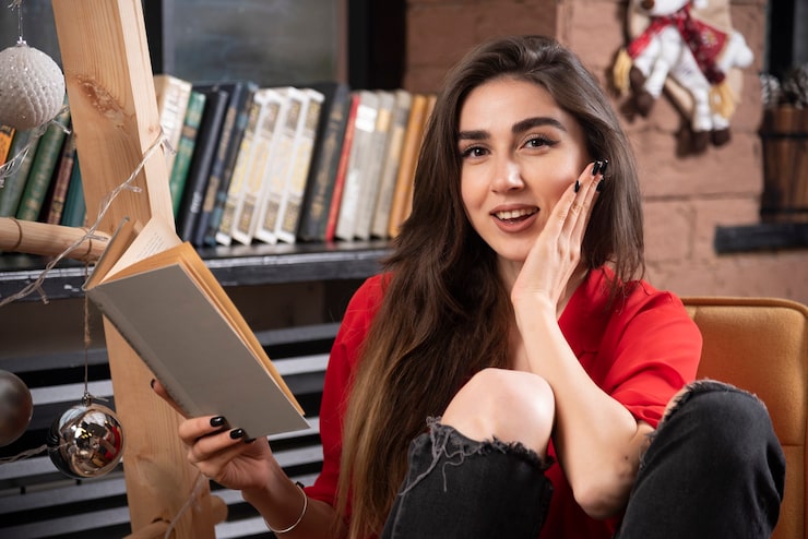 Gratis Foto een jonge vrouw model zit en houdt een boek vast.