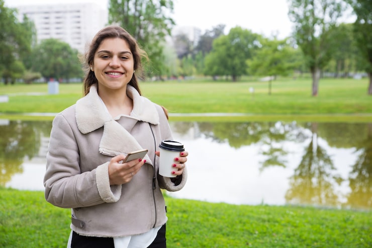 Gratis Foto gelukkig blij meisje met telefoon genieten van afhaalmaaltijden koffie