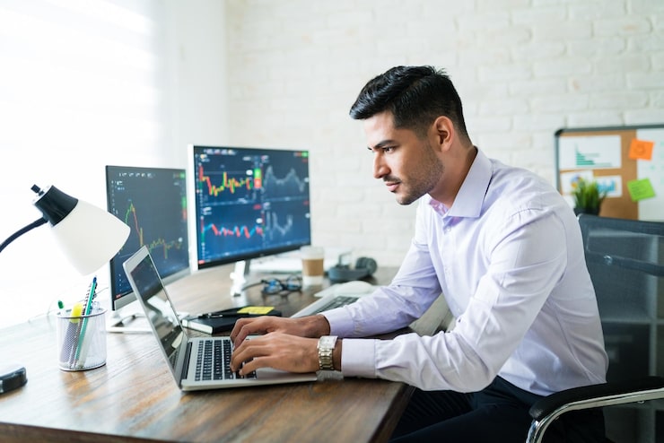Gratis Foto knappe latijnse freelance-makelaar die handelt via laptop aan bureau terwijl hij thuis werkt