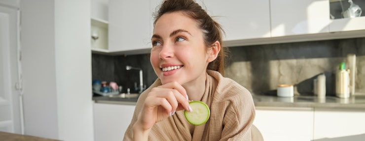 Gratis Foto portret van een gelukkige glimlachende jonge vrouw in de keuken die courgette snijdt met groenten