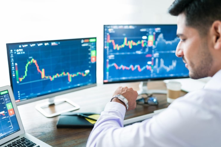Gratis Foto zelfverzekerde mannelijke effectenmakelaar die wacht tot de beurs opengaat en op zijn horloge voor zijn computer kijkt